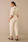 Shop Ampm Ivory Linen, Faux Leather Brooches, Embroidery Placed Flower Pattern Jumpsuit at Aza Fashions Shop_Ampm_Ivory Linen, Faux Leather Brooches, Embroidery Placed Flower Pattern Jumpsuit_at_Aza_Fashions