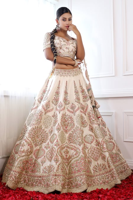 CREAM IVORY BANARASI LEHENGA SET AND A MIRROR EMBROIDERED CONTRAST RED  BLOUSE PAIRED WITH A MULTI COLOURED EMBROIDERED PATCHWORK DUPATTA AND LIGHT  GOLD EMBELLISHMENTS. - Seasons India