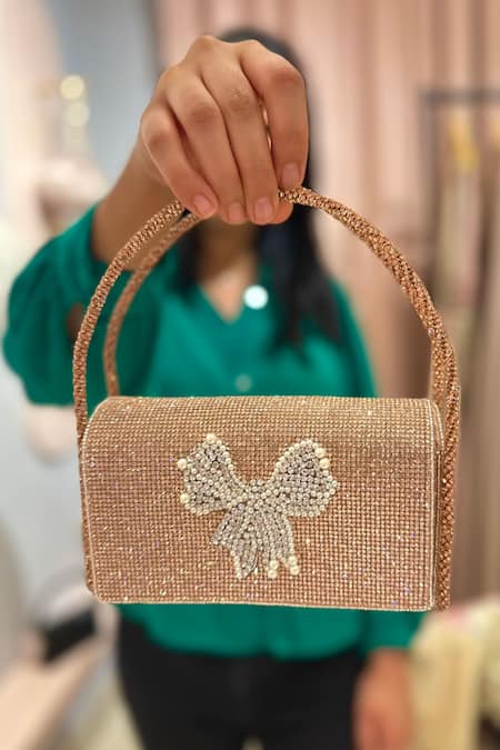 Ozel Rose Gold Crystal Bow Embellished Flap Bag Online at Aza Fashions Ozel_Rose Gold Crystal Bow Embellished Flap Bag _Online_at_Aza_Fashions