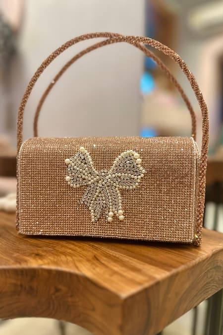 Shop Ozel Rose Gold Crystal Bow Embellished Flap Bag at Aza Fashions Shop_Ozel_Rose Gold Crystal Bow Embellished Flap Bag _at_Aza_Fashions
