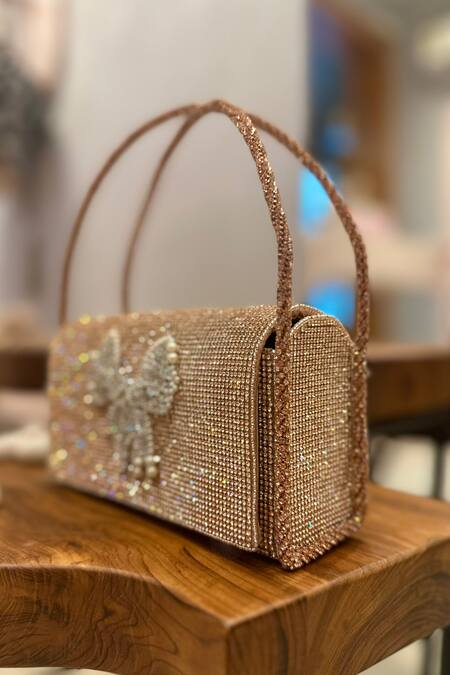 Buy Ozel Rose Gold Crystal Bow Embellished Flap Bag Buy_Ozel_Rose Gold Crystal Bow Embellished Flap Bag