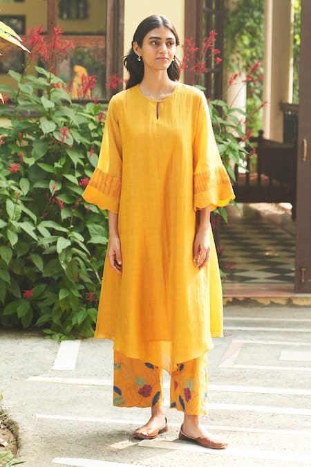 Shop Vaayu Yellow Muslin Applique Round Neck Asymmetric Flared Sleeve Kurta And Pant Set Online at Aza Fashions Shop_Vaayu_Yellow Muslin Applique Round Neck Asymmetric Flared Sleeve Kurta And Pant Set _Online_at_Aza_Fashions