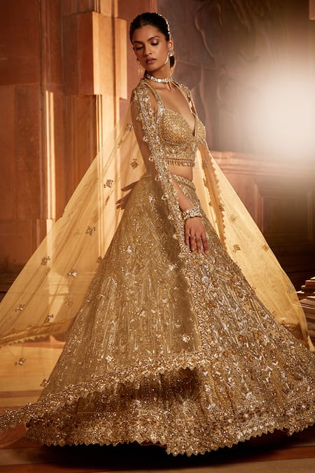 This gold lehenga set features an exaggerated flare at the back, showcasing  a free-flowing trail.... | Lehenga, Golden bridal lehenga, Indian bridal  dress