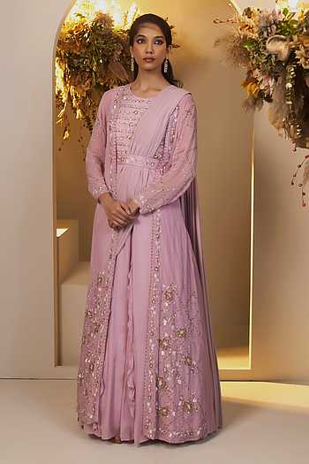 pink saree dress Sequined Blush pink Saree-Style Gown: This ensemble features a heavily embellished lavender or dusty rose fabric with intricate sequin work. The blouse has cold-shoulder sleeves adorned with delicate beaded fringe, while the