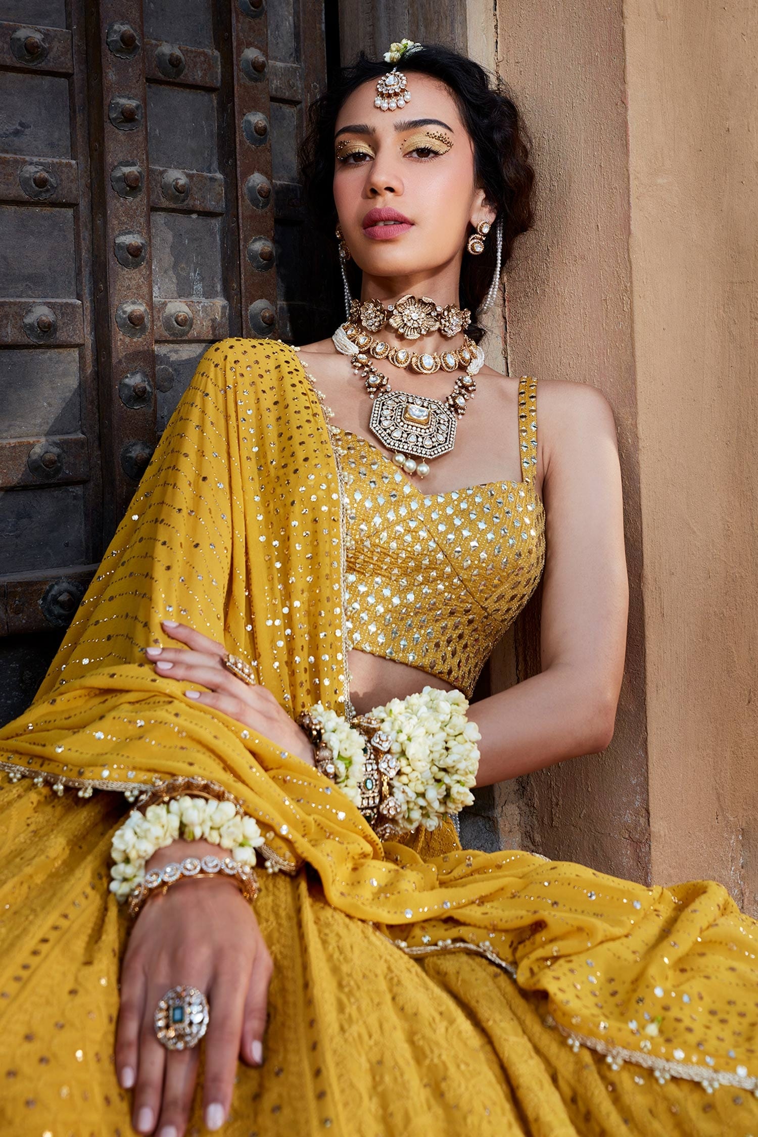 Photo of Bride wearing a pastel pink lehenga with a yellow dupatta and  emerald jewellery.